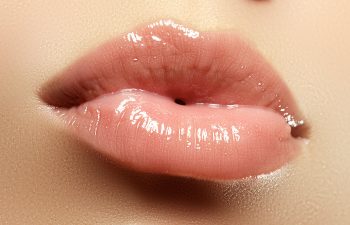 Glossy, pink lips close-up, with visible texture and shine., 