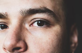 A young man stares at the camera. Brown man's eyes close up. Male face close up., 